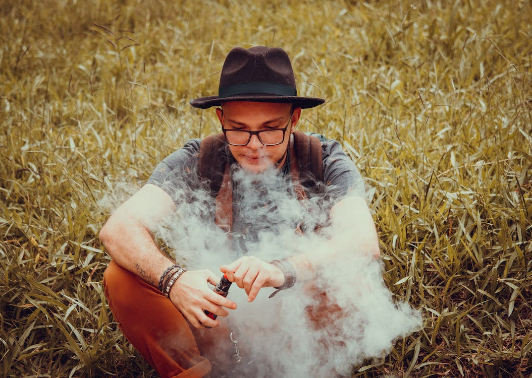 A person sitting on the grass and vaping