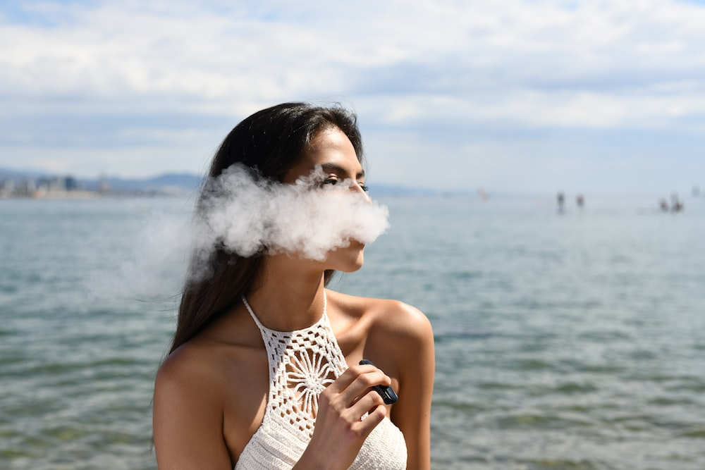 a woman vaping by the beach.
